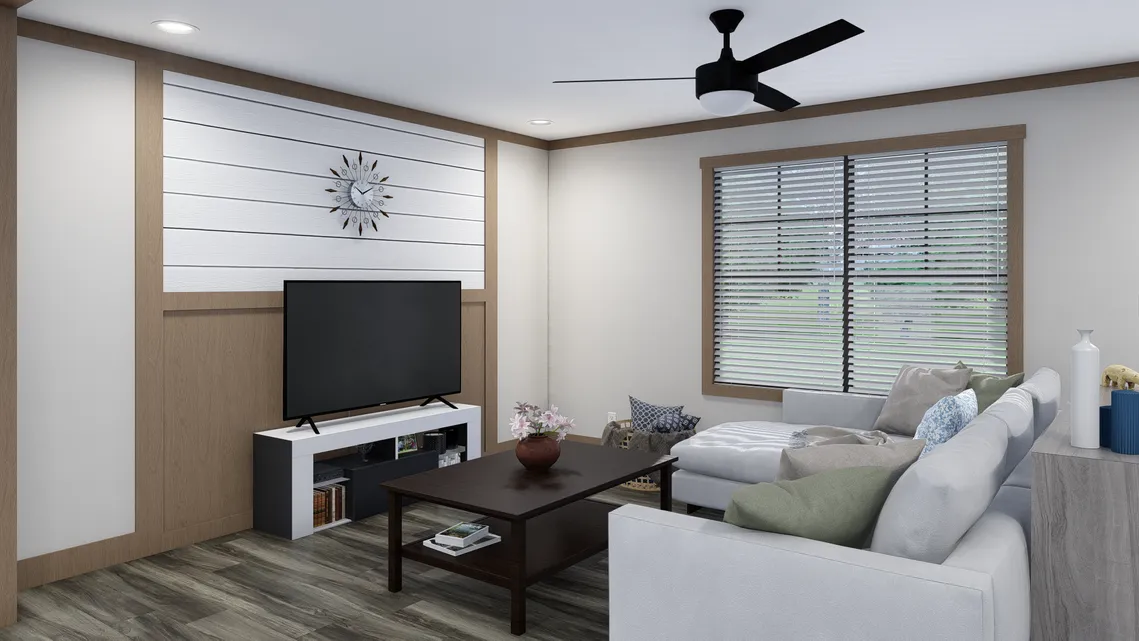 Modern living room with a sectional sofa, coffee table, television on a stand, decorative clock on the wall, ceiling fan, and large window with blinds.