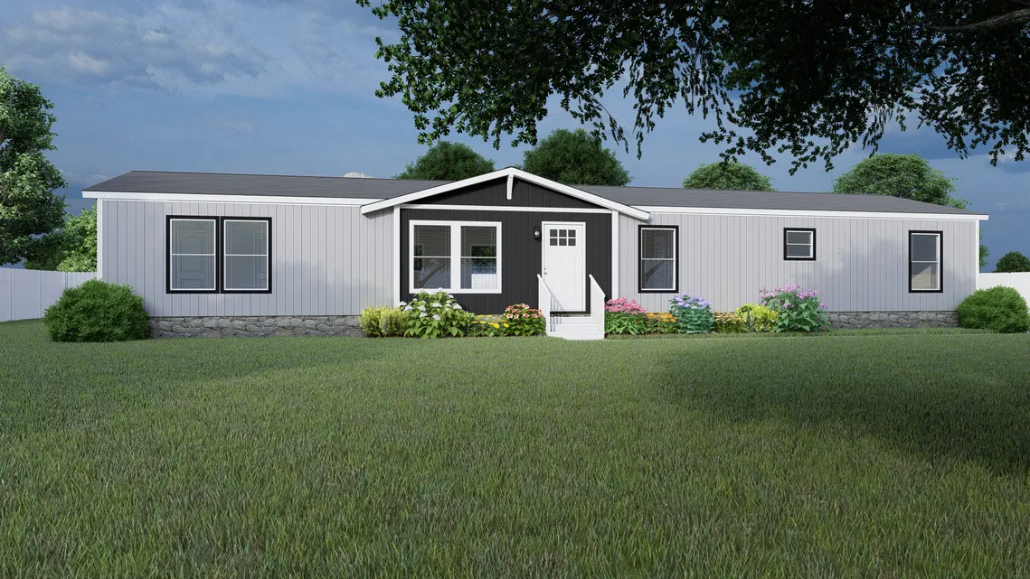 A white and black manufactured home with a front porch, surrounded by green grass, shrubs, and flowers, under a partly cloudy sky.