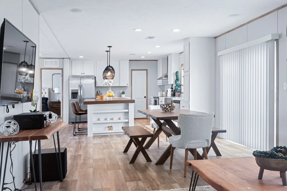 Modern open-concept kitchen and dining area with wood flooring, white cabinets, stainless steel appliances, and natural light from sliding glass doors.