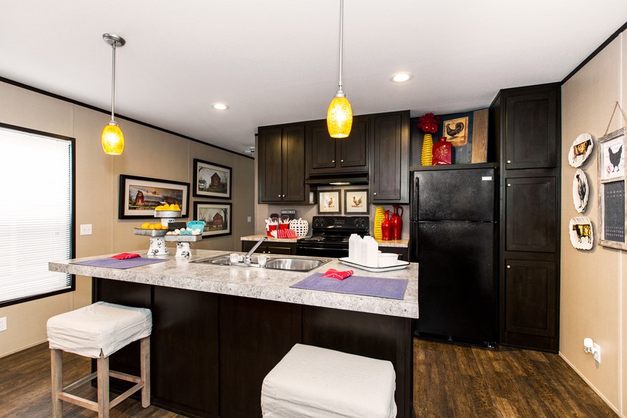 Modern kitchen with dark cabinets, a marble-patterned island with two stools, yellow pendant lights, and rooster-themed decor on the walls and shelves.